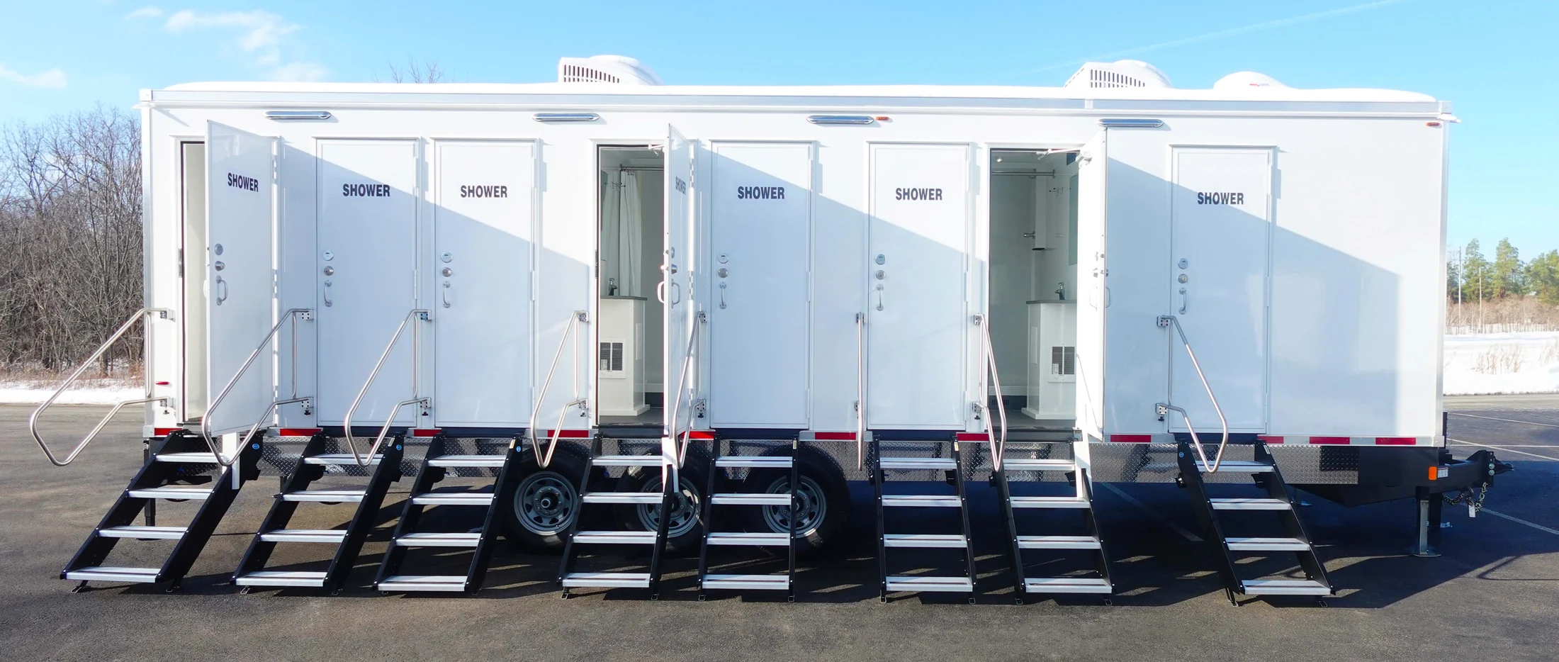 Side view of an eight-station shower trailer with SHOWER on every door and a set of steps under each one