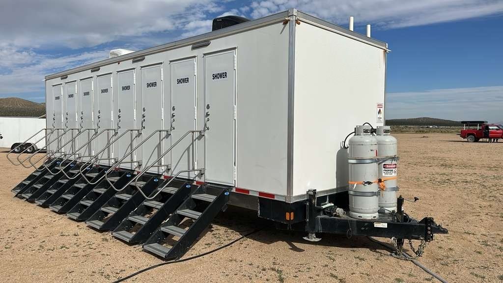 Eight-door shower trailer on a remote desert jobsite with a water hose connected